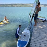 Das Windsegel wird vom Steg auf das Surfbrett heruntergelassen